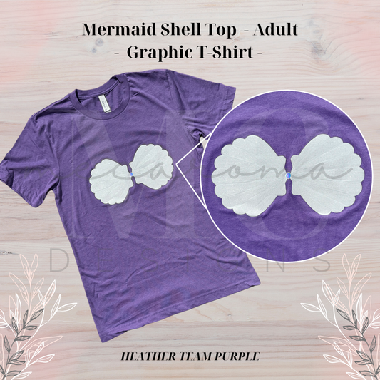 Heather team purple adult t-shirt with a graphic of a white mermaid shell bra top across the chest, shown on a light wood background with floral accents and a close-up inset of the shell design.